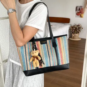 Detailed showcase of colorful woven straw tote bag with black leather and cute bear charm.