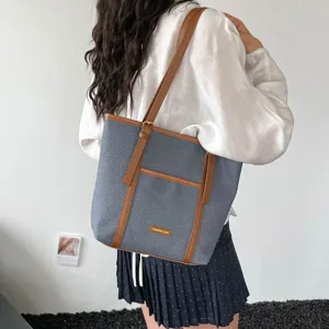Detailed view of blue woven shoulder tote bag with brown leather trim and front pocket design.