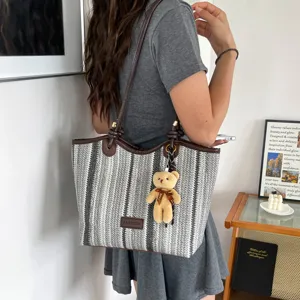 Casual striped straw tote bag for women with cute bear pendant and comfortable shoulder straps.
