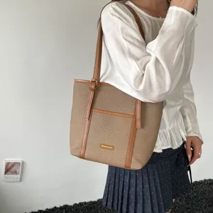 Stylish woven commuter tote bag detail showing shoulder strap and front pocket design.