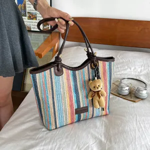 Detailed view of the colorful woven straw tote bag with brown leather handles and cute bear.