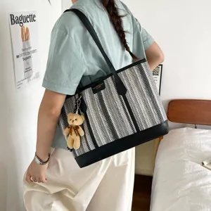 Woven tote bag for women, large capacity shoulder bag with stylish black trim and bear charm.
