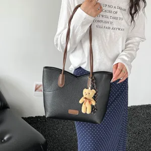 Women black textured leather tote bag with brown shoulder straps and cute bear pendant.