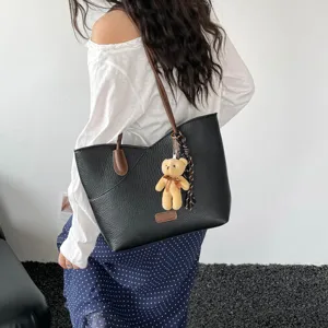 Detailed view of black PU leather tote bag with brown straps and cute bear pendant charm.
