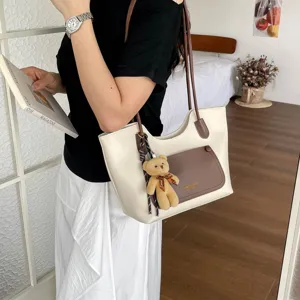 Gros plan détaillé du sac cabas bicolore décontracté avec un joli pendentif d'ours en peluche.