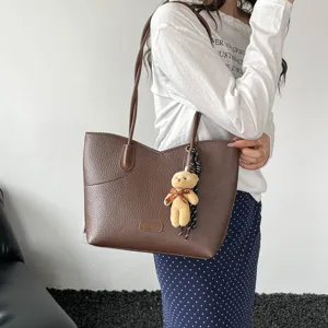 Brown PU leather tote bag detail shot featuring textured finish and cute bear keychain.