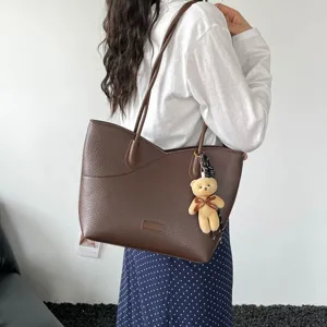 Stylish brown PU leather tote bag for women, chic shoulder bag with bear charm for commute.