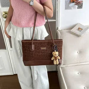 Vista dettagliata della elegante borsa tote marrone maculata con ciondolo a forma di orsetto.