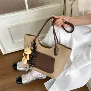 Vue détaillée du sac cabas bicolore élégant pour femme avec charmant pendentif d'ours.