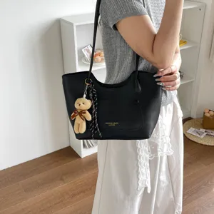 Vue détaillée du sac cabas fourre-tout noir en cuir pour femme avec pendentif ours et poche.