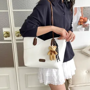 Trendy contrast color tote bag for women, stylish shoulder bag with cute bear pendant detail.