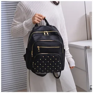 Detailed view of women's black nylon backpack with quilted studs and gold zippers for daily use.
