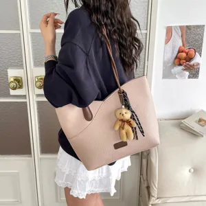 Trendy women PU leather tote bag with cute bear pendant and contrast design for commute.