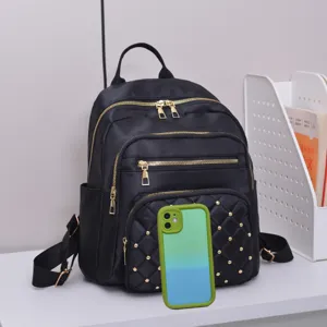 Classic black nylon backpack with gold zippers, multiple compartments and chic front rivet design.