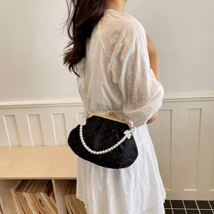 Vue détaillée d'un sac coquillage noir plissé avec anse en perles et monture dorée.
