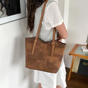 Detailed view of the brown geometric tote bag worn on shoulder, showing straps and buckles.