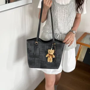 Detailed closeup view of stylish grey plaid tote bag with cute bear charm carried by model
