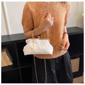 Vintage white lace evening bag detail, pearl bow decoration and metal chain strap style.