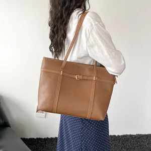 Retro brown leather tote bag detail showcasing large capacity and stylish buckle strap design