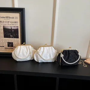 Élégant sac bandoulière coquillage plissé avec poignée en perles et fermoir métallique.