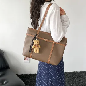 Detailed shot of retro brown textured tote bag with cute teddy bear pendant and belt.