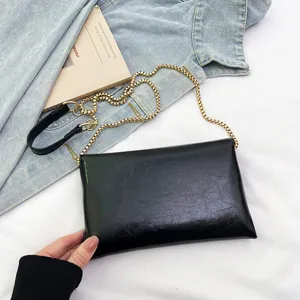 Detailed close-up of black textured crossbody bag featuring gold chain and PU leather strap.