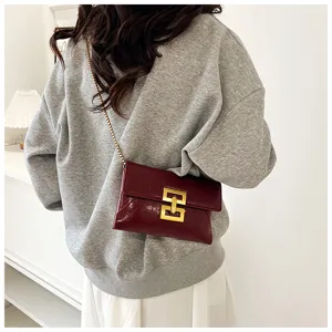 Detailed view of the dark red patent leather chain crossbody bag worn by female model.