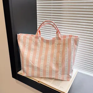 Pink striped canvas tote bag detail shot showing bow pattern and durable double handles.