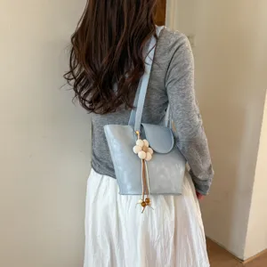 Stylish light blue women's shoulder tote bag with floral charm for daily commuting outfit.