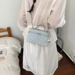 Detailed lifestyle view of a cute light blue polka dot box shoulder bag worn by a model.