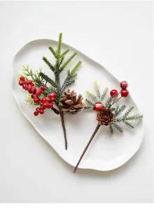 Artificial Christmas pine branch detail with red berries and pine cones for holiday decor.
