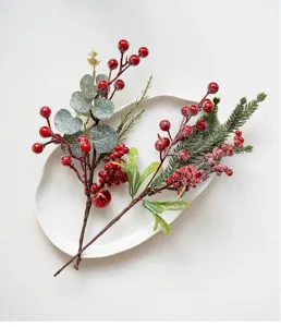 Close-up detail of artificial Christmas red berry and pine needle branches for festive decor.