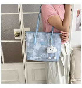 Détail de sac cabas à carreaux bleu clair avec joli pendentif nuage et poignées.