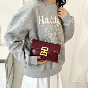 Chic women's patent leather crossbody bag with stylish gold hardware and metal chain strap.