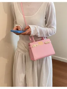 Detailed view of a stylish pink leather shoulder bag with gold hardware and top handles.