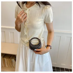 Stylish mini handbag with round handle and metallic chain strap, chic and compact detail view.