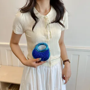 Mini sac bandoulière scintillant bleu avec poignée ronde métallique pour un détail élégant.