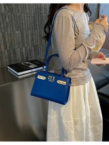 Detailed view of fashionable blue leather shoulder bag with metal closure and handle in modern scene.