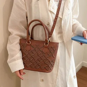 Brown leather bucket handbag with stylish embossed grid pattern for women casual daily use.