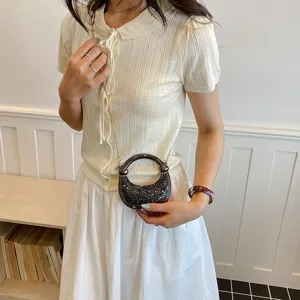 Stylish women fashion outfit set with knit short sleeve top, white skirt and mini round handle bag.