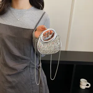 Gros plan sur le sac a main tendance argente avec poignee anneau et bandouliere chaine.
