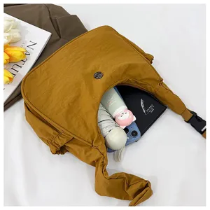 Detail view of the mustard yellow nylon hobo bag shows inner capacity and daily props.