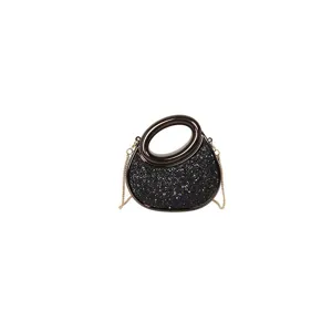 Élégant sac à bandoulière noir brillant avec poignée ronde et chaîne dorée pour femmes.
