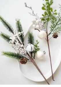 Detail view of artificial Christmas floral picks with pine needles, white berries and pinecones.