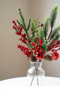 Close-up of artificial pine branches with red berries and pinecones for Christmas decor.