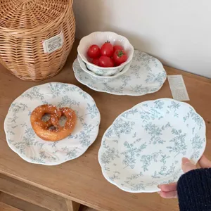 Detailed shot of French vintage ceramic plate with blue floral relief, elegant tableware styling.