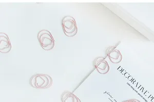 Detailed flat lay shot of cute pink heart-shaped paper clips, aesthetic stationery design.