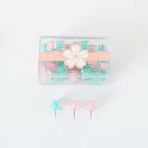 Vue détaillée de punaises carrées colorées dans une boîte transparente avec ruban.