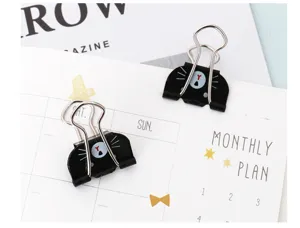 Close-up detail of cute black cat metal binder clips on planner page, office stationery supply