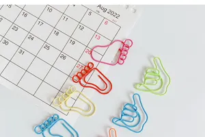 Close up of creative cute colored metal paper clips with fun foot and hand gesture shapes.